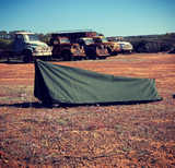 green canvas swag in outback australia trucks in background blue sky